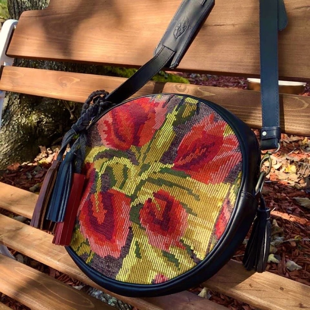Round crossbody bag (Redondo). Woven tulip panel. Full grain black leather.